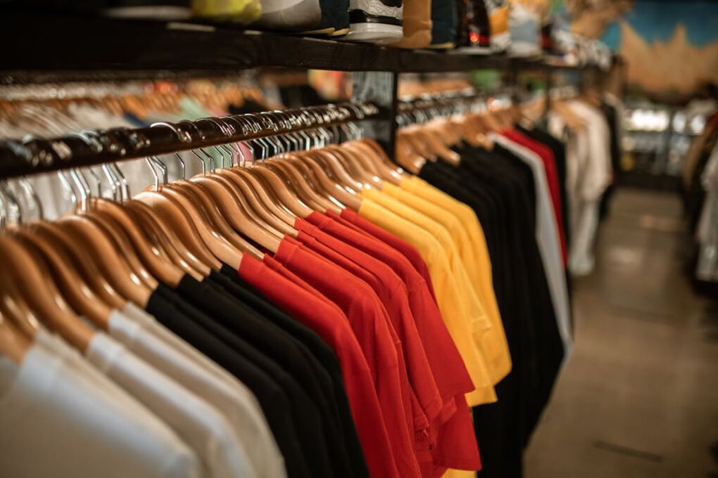 Free Clothing store display with shirts hanging neatly on a rack indoors. Stock Photo