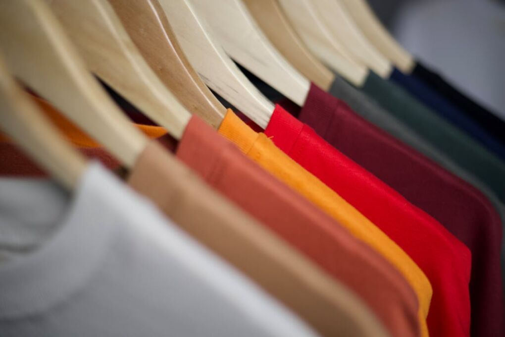 Free Close-up of colorful T-shirts arranged on wooden hangers, highlighting fashion display. Stock Photo